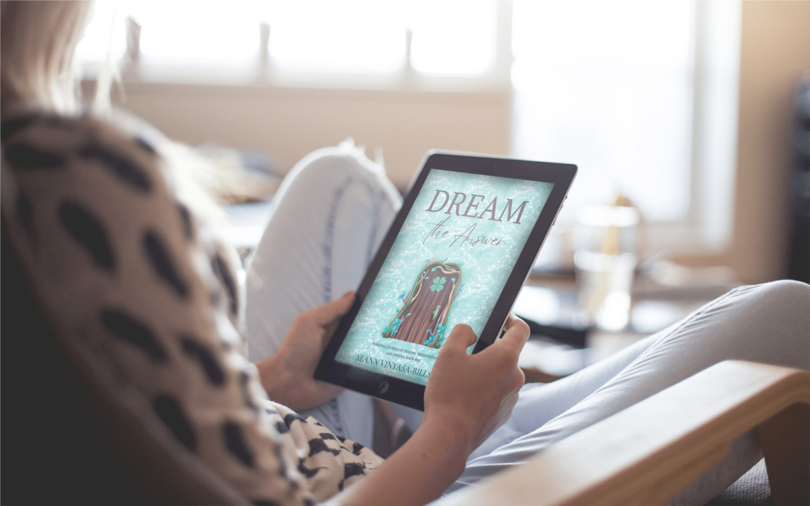 A woman holding an Ipad that shows the front cover of the ebook - Dream The Answer